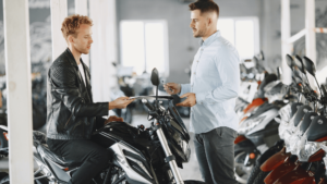 A motorcycle salesman selling a motorbike to a biker customers in a motorcycle dealership store.
